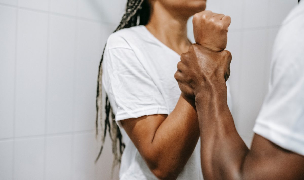 domestic abuse: a Black man holds the wrist of a Black woman in a threatening manner