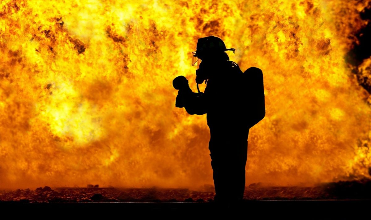 a firefighter standing in front of a wall of flames